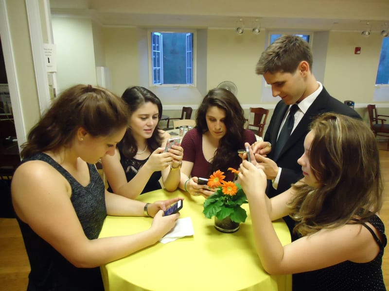 Jóvenes sentados juntos usando sus teléfonos inteligentes.